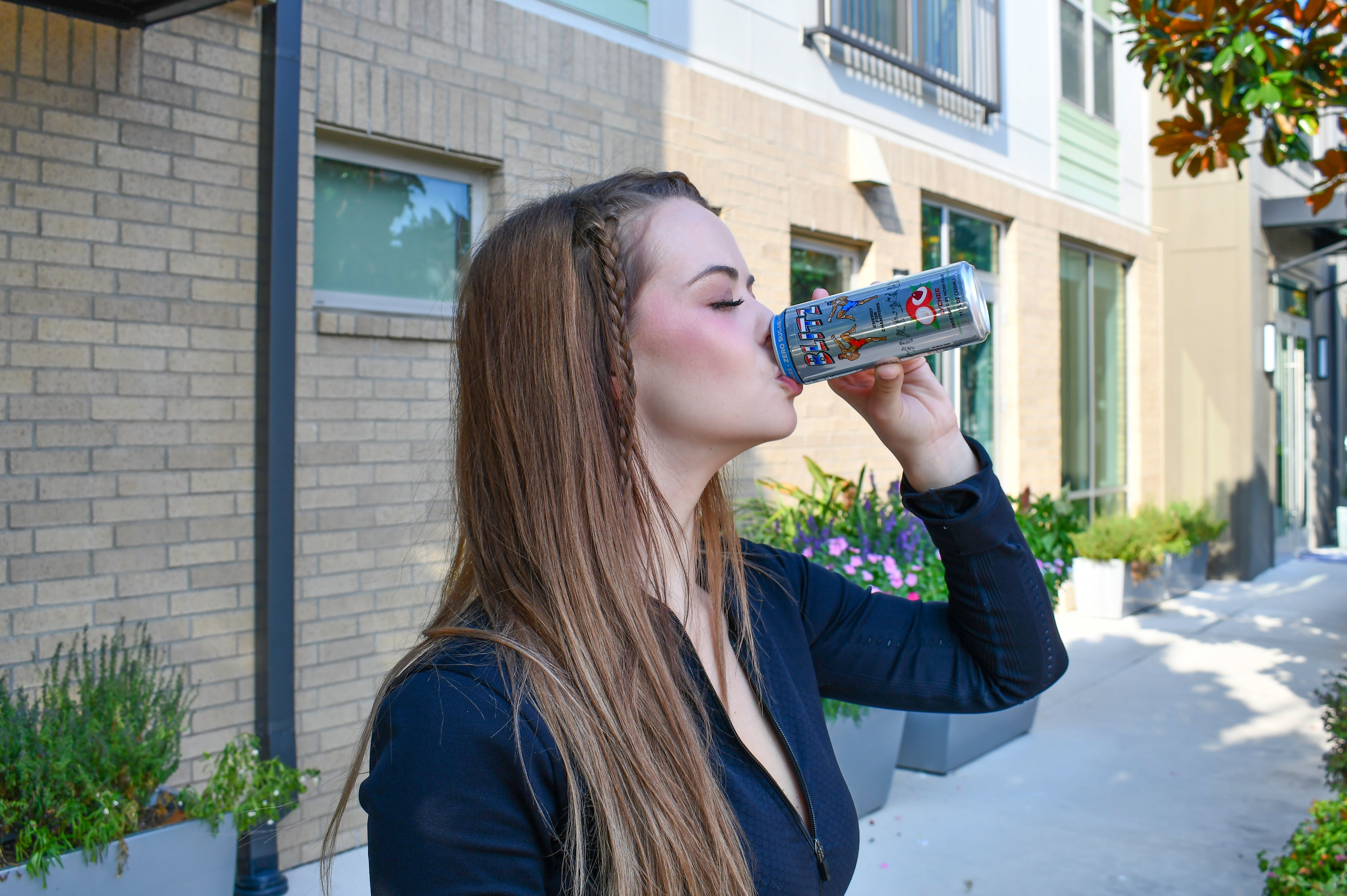 Woman drinking from a water bottle outdoors on a sunny day
